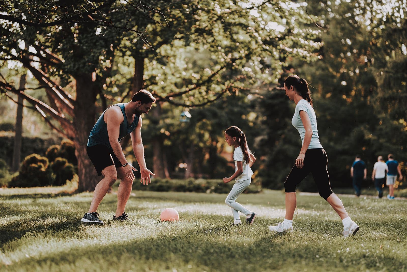 Athletic family playing sports in park.