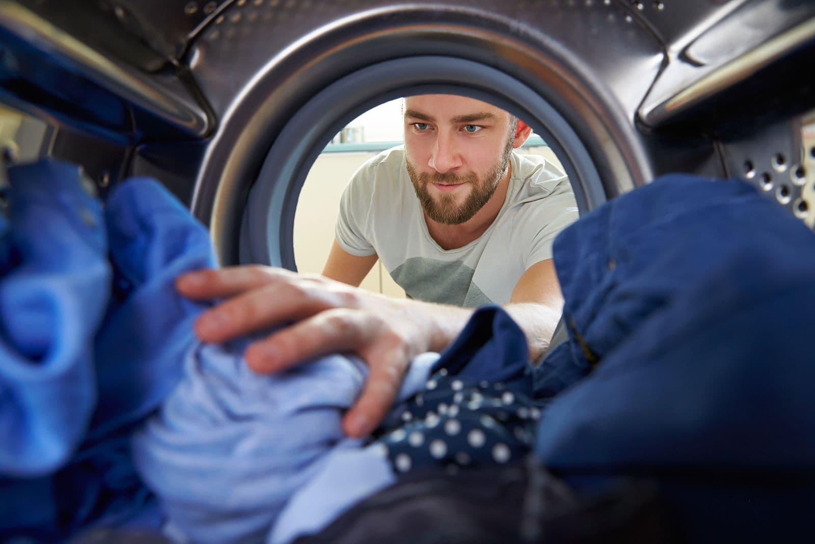 Man doing laundry reaching inside.